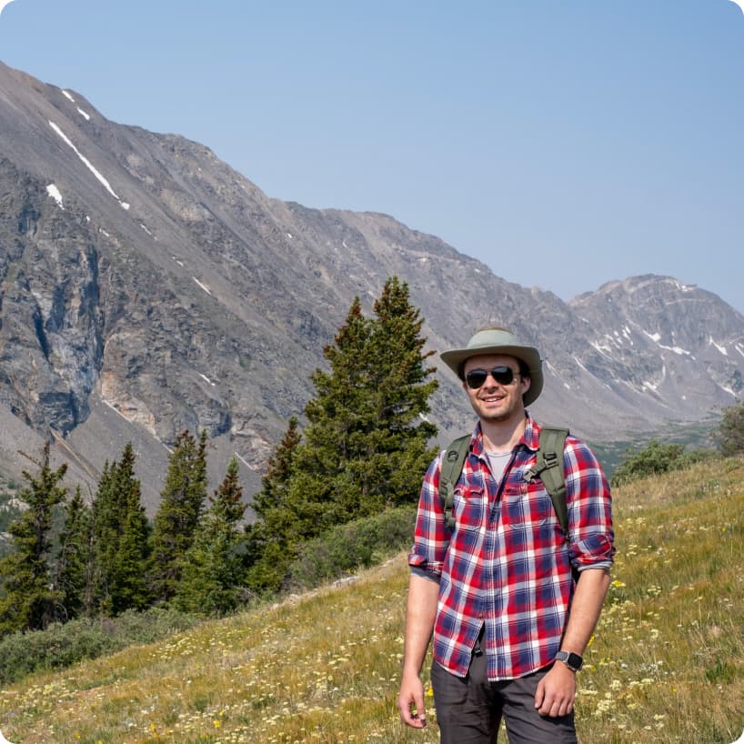 Alex Gordienko standing on an alpine hillside above a mountain valley.